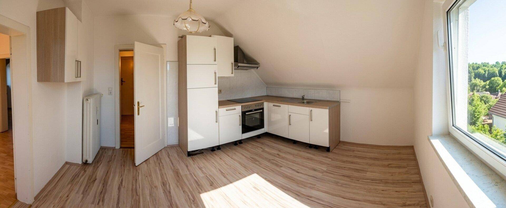 Dachgeschossküche mit Einbauküche, Laminatboden und großem Fenster mit Ausblick.