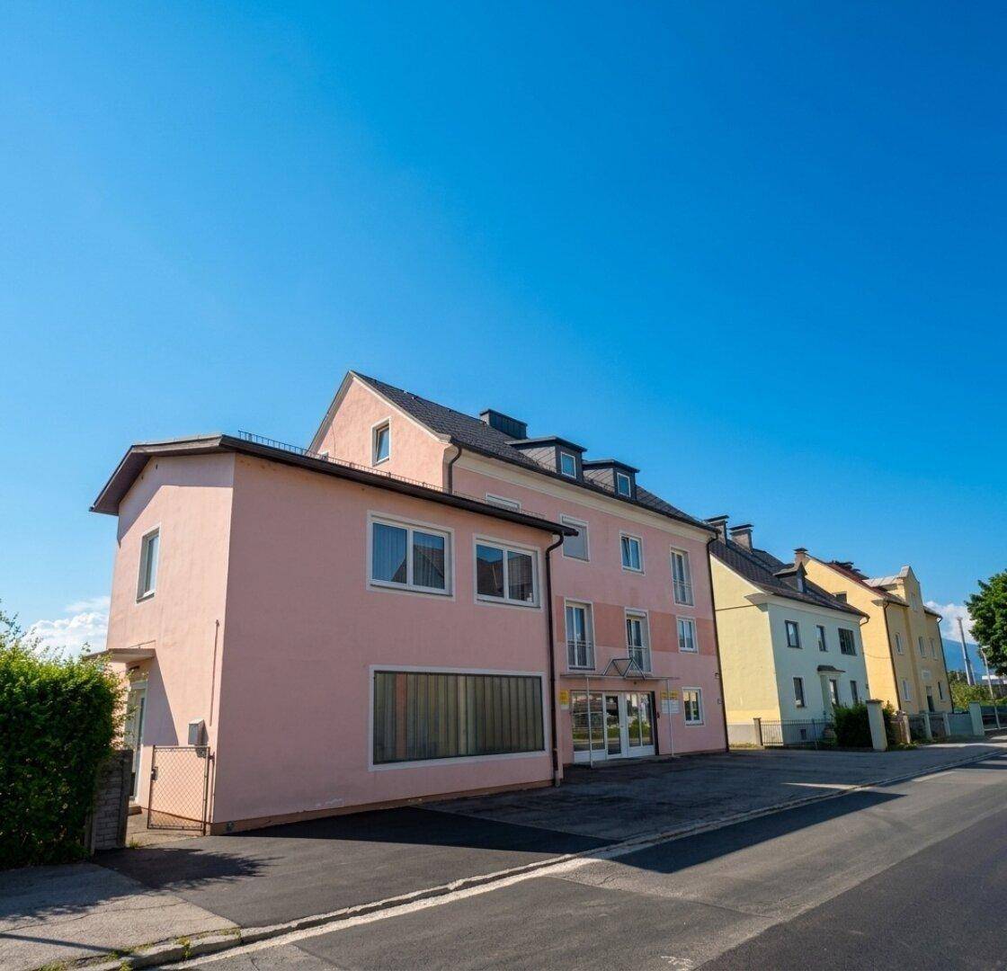Reihe von Mehrfamilienhäusern in verschiedenen Farben entlang einer Straße unter blauem Himmel.