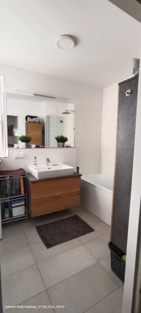 Modernes Badezimmer mit Badewanne, Einzelwaschbecken und großem Spiegel.