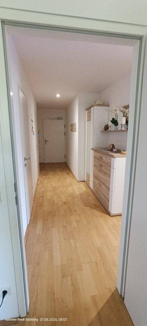 Heller Flur mit Holzboden und modernen Möbeln, der zu weiteren Räumen führt.