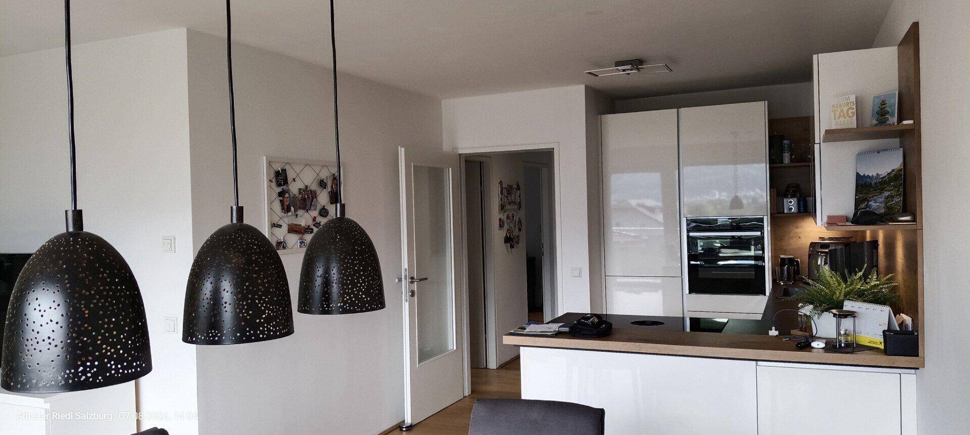 Offener Wohnbereich mit Essplatz, modernen Pendelleuchten und integrierter Küche.