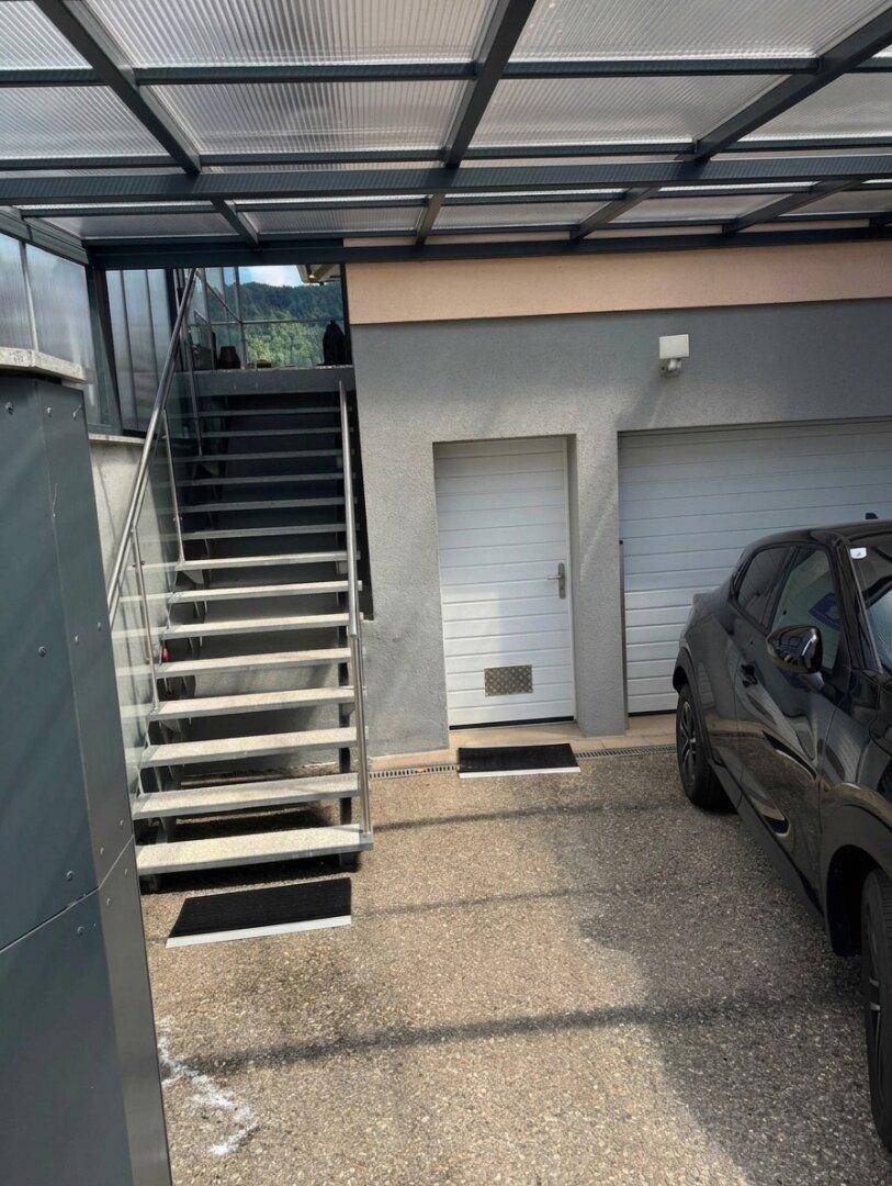 Garagenzufahrt mit zwei Garagentoren, Nebeneingang und Außentreppe zum Obergeschoss.