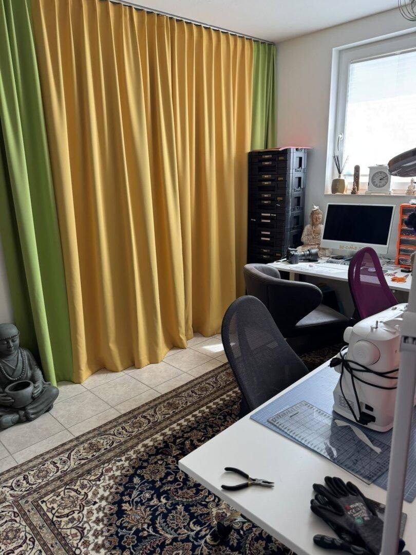 Kreativer Arbeitsbereich mit bunten Vorhängen, Schreibtisch und Nähmaschine.