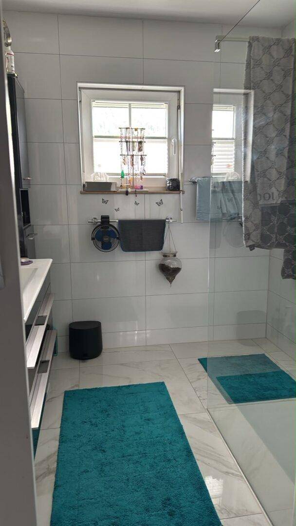 Modernes Badezimmer mit weißen Fliesen, Fenster und begehbarer Dusche.