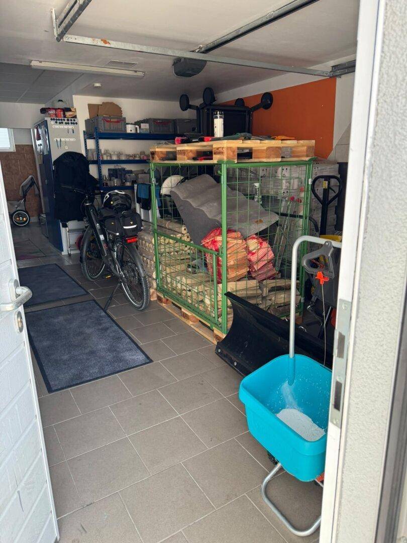 Geräumige Garage oder Abstellraum mit Fliesenboden und verschiedenen Lagergegenständen.