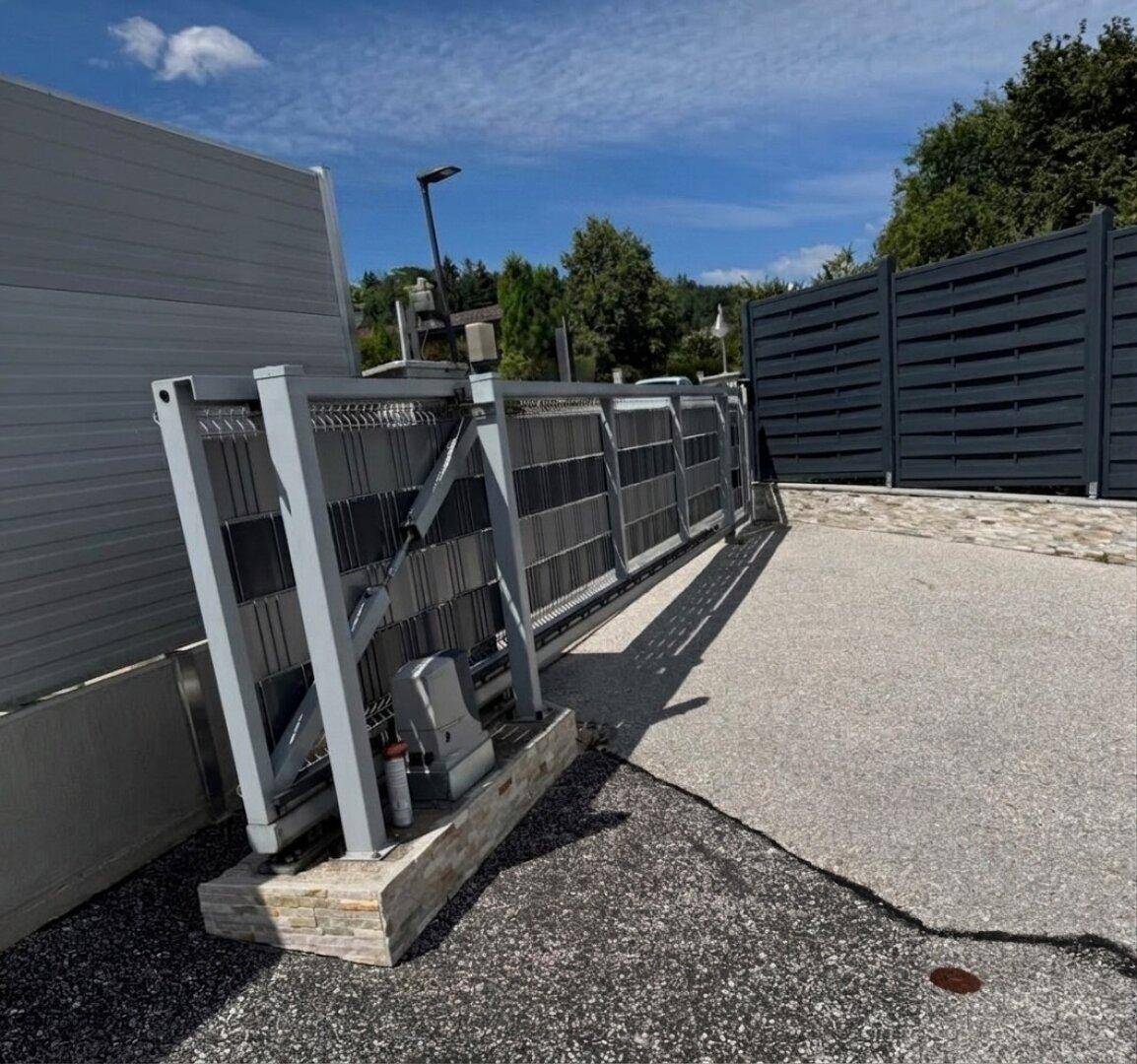 Automatisches Schiebetor aus Metall, das die Einfahrt zum Grundstück sichert.