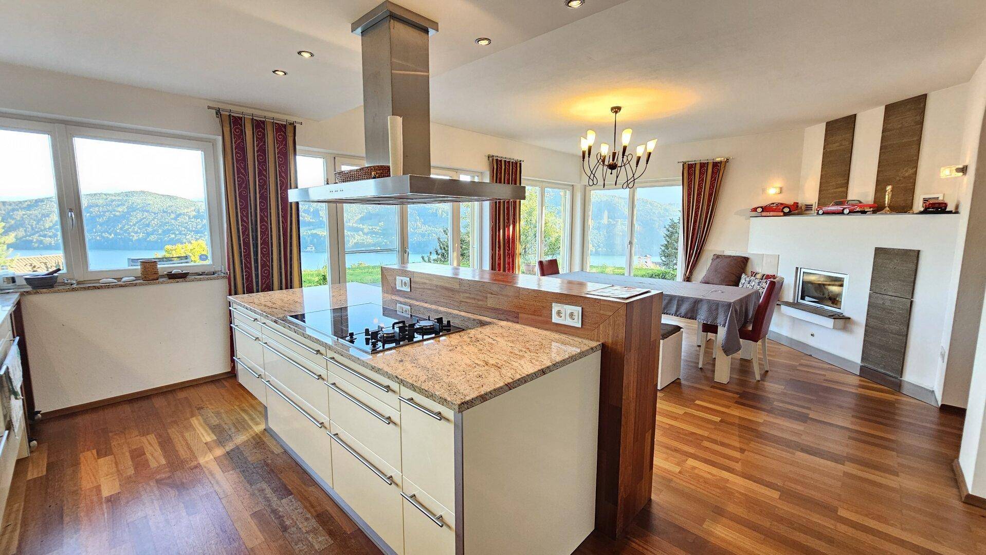 Offene Küche mit Essbereich, Seeblick, Kücheninsel mit Kochfeld und einem modernen Kamin.