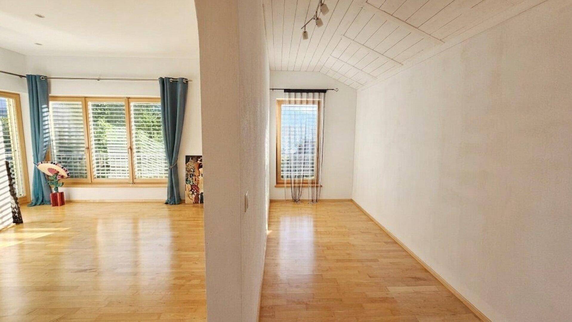 Heller Raum mit hellem Holzboden und Fenstern mit Jalousien, bereit zur individuellen Gestaltung.