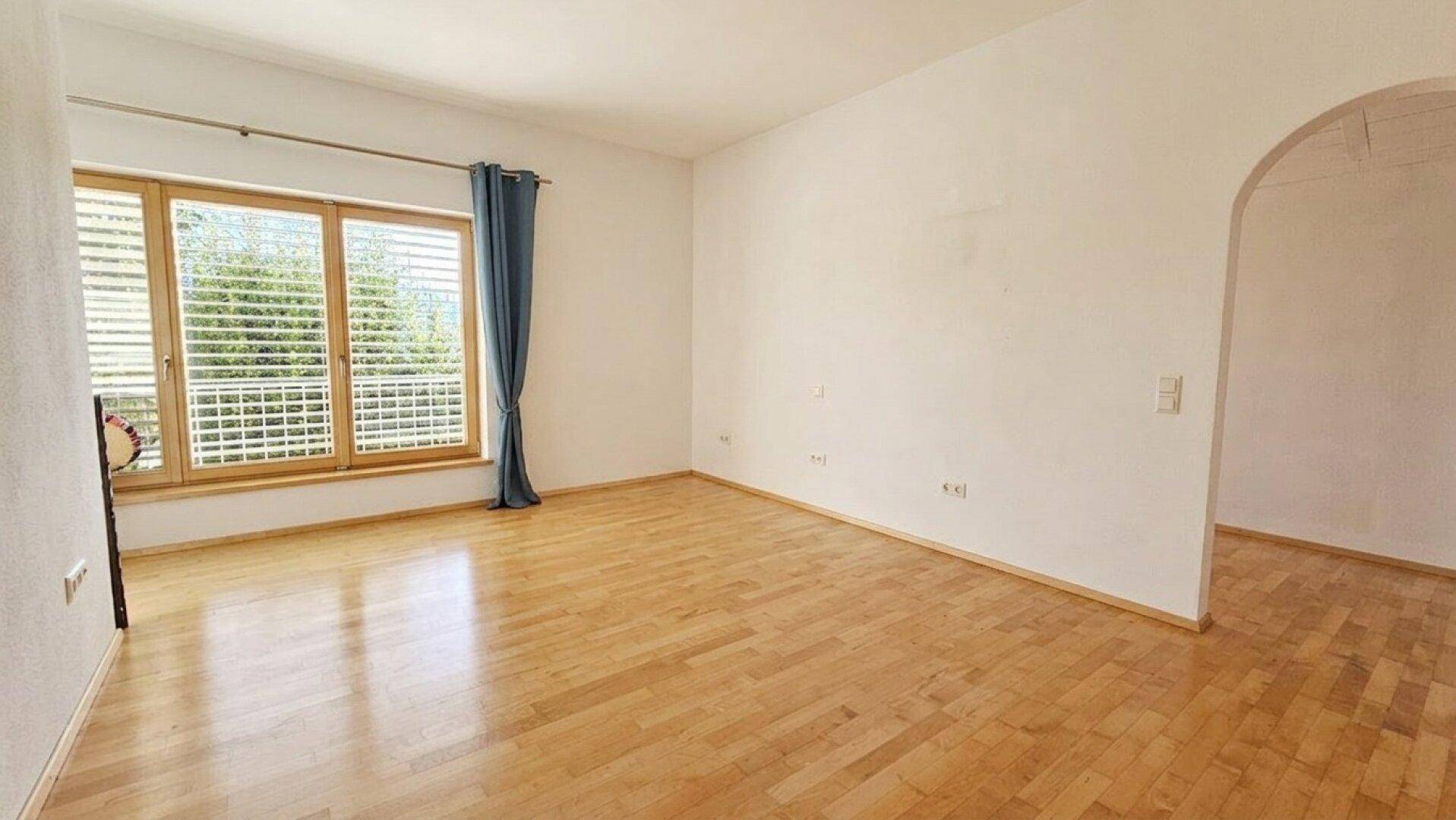 Geräumiger, heller Raum mit Holzboden und großen Fenstern, der vielseitig genutzt werden kann.