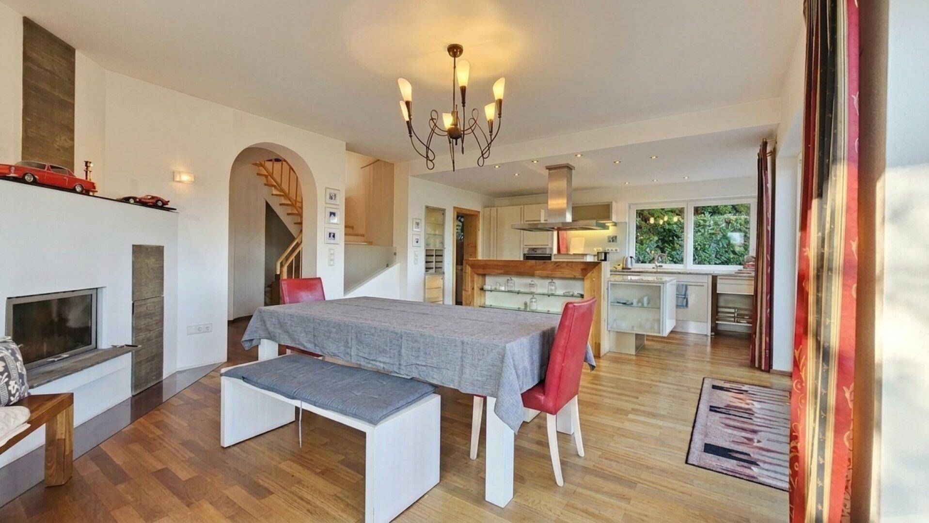 Geräumiger Essbereich mit großem Tisch, Sitzbank und Kamin, offen zur Küche und Treppe.