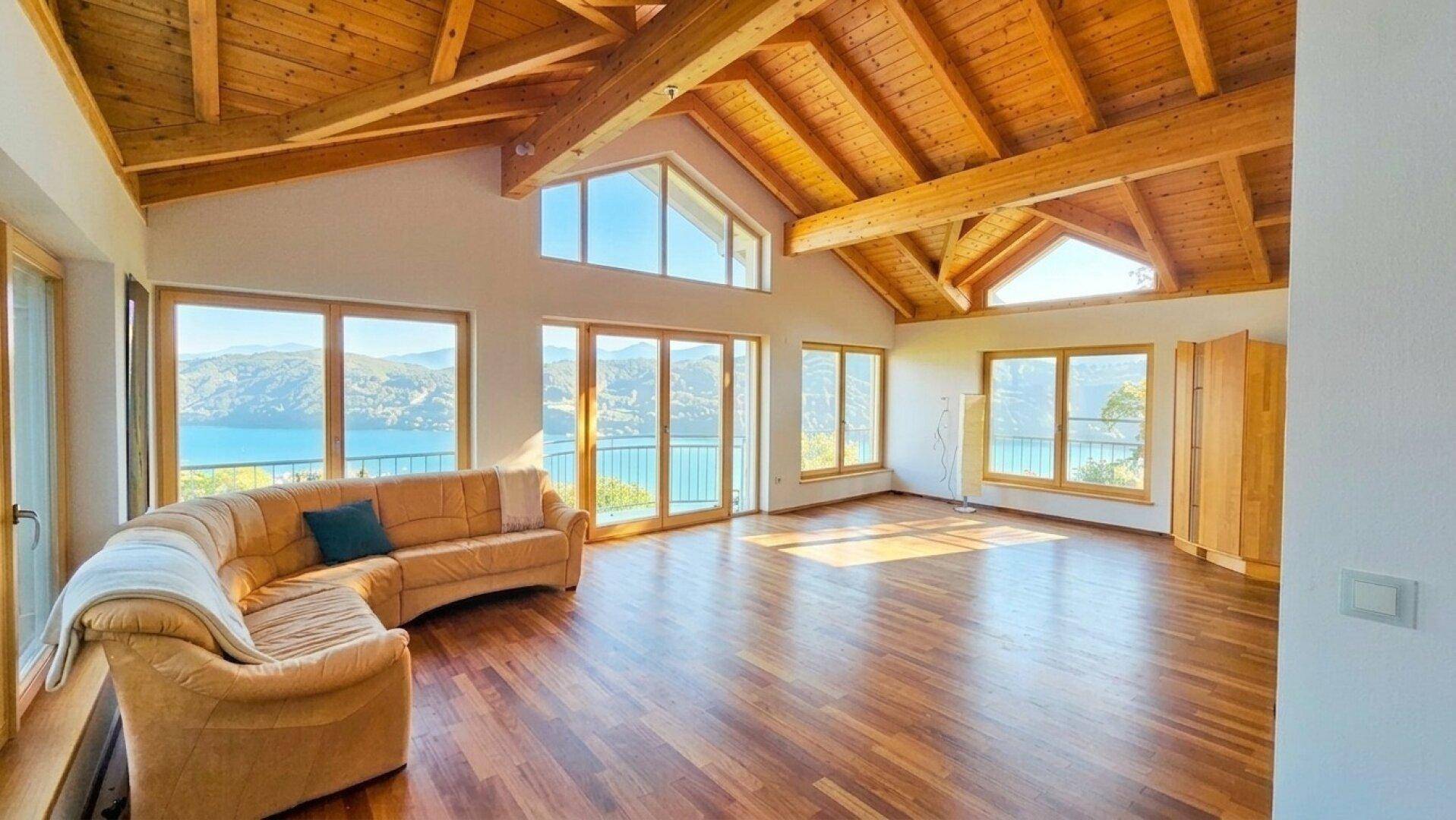 Weitläufiges Wohnzimmer mit atemberaubendem Seeblick durch große Fenster und einer gemütlichen Sofaecke.