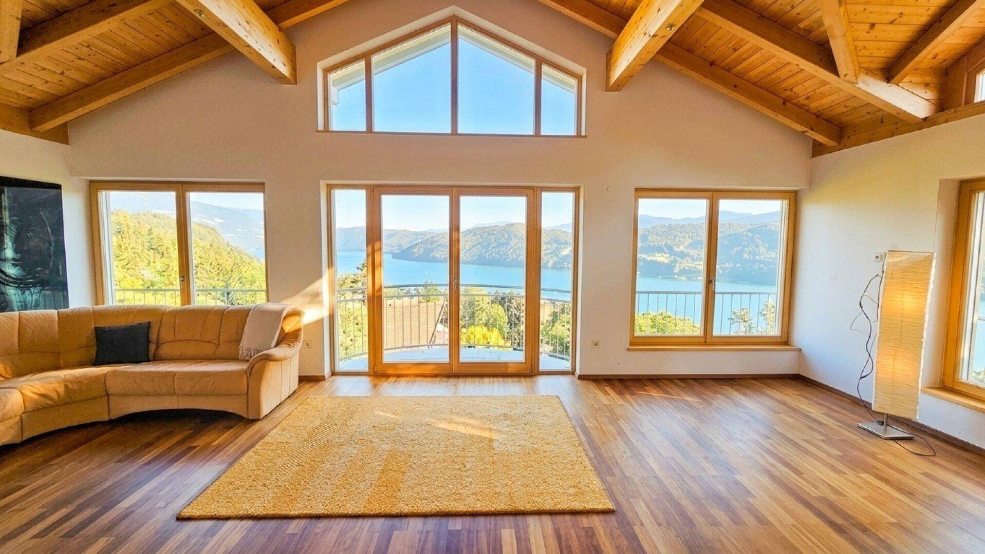 Großzügiges Wohnzimmer mit hohen Holzdecken und Panoramafenstern, die einen atemberaubenden Seeblick bieten.