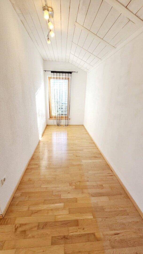 Helles Zimmer mit Holzboden und schräger Holzdecke, ideal als Schlaf- oder Arbeitszimmer nutzbar.