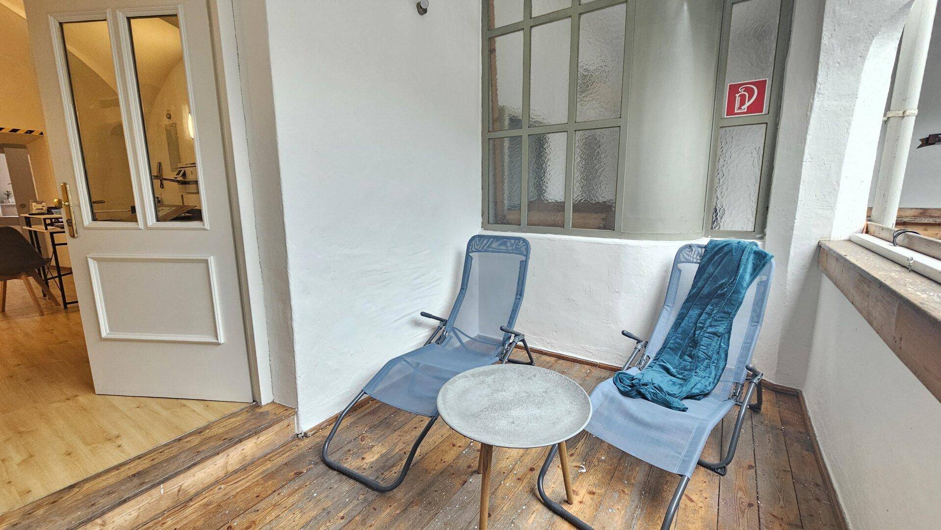 Gemütliche Loggia mit zwei Liegestühlen und einem kleinen Tisch, ideal zum Entspannen.
