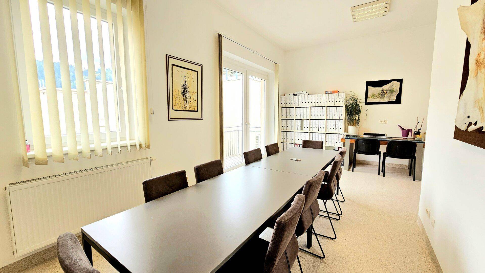 Großer Konferenzraum mit langem Tisch, vielen Stühlen und Zugang zu einem Balkon.