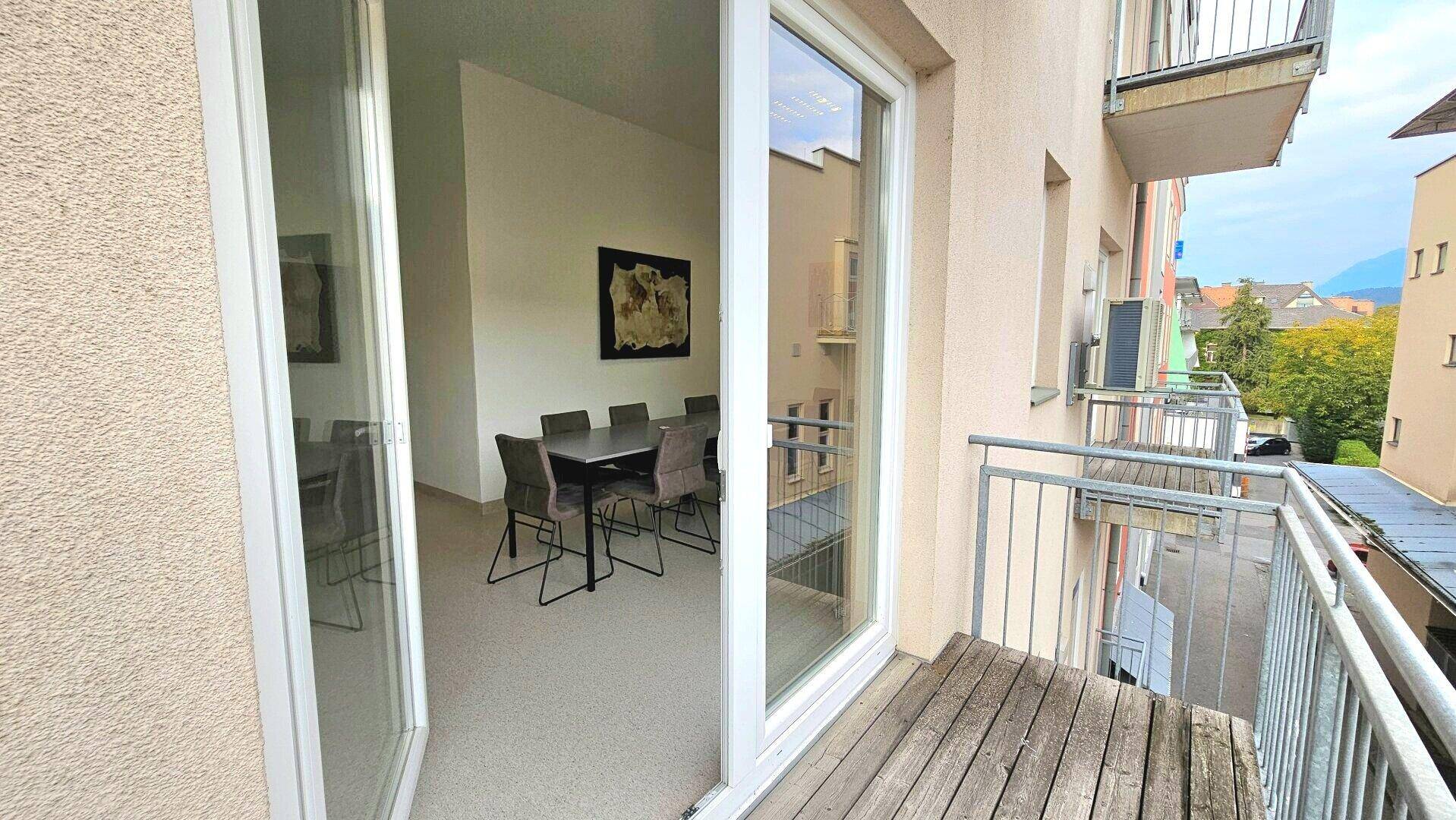 Balkon mit Holzboden und Metallgeländer, bietet Blick auf die Umgebung.