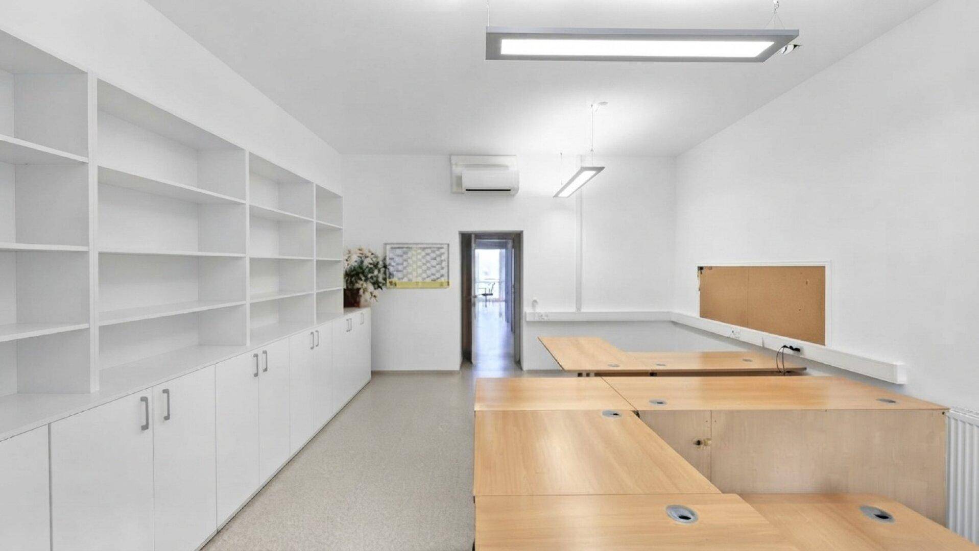 Leeres Büro mit weißen Regalen, Schränken und vorbereiteten Arbeitsplätzen.