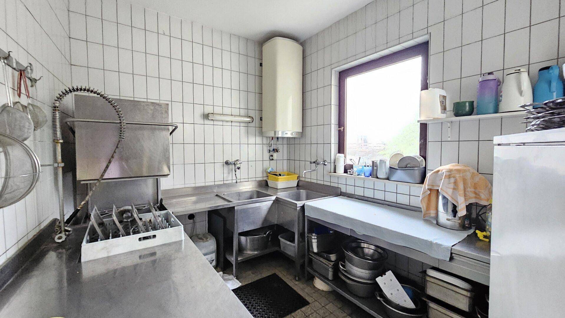 Funktionale Küchenzeile mit Spülbecken, Warmwasserbereiter und einem Fenster für Tageslicht und Belüftung.