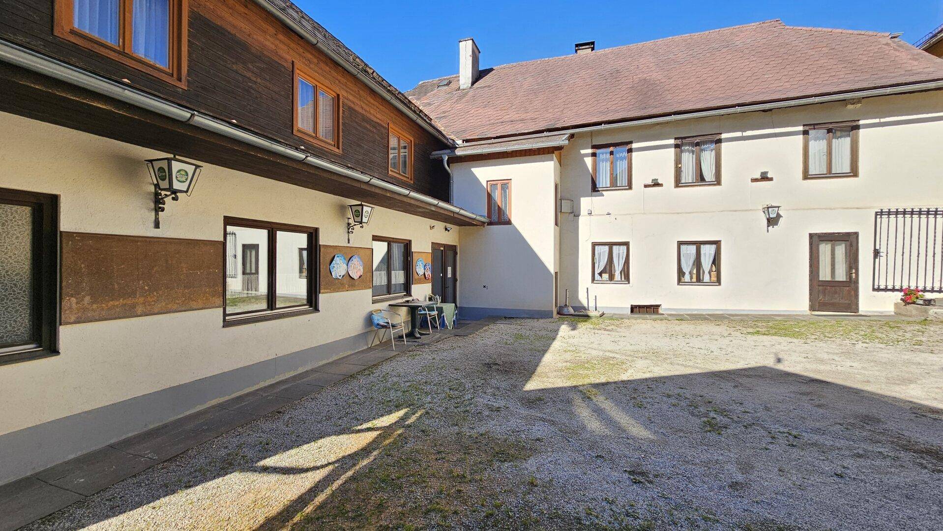 Sonniger Innenhof mit Kiesboden zwischen zwei Gebäuden, ideal für eine ruhige Pause im Freien.