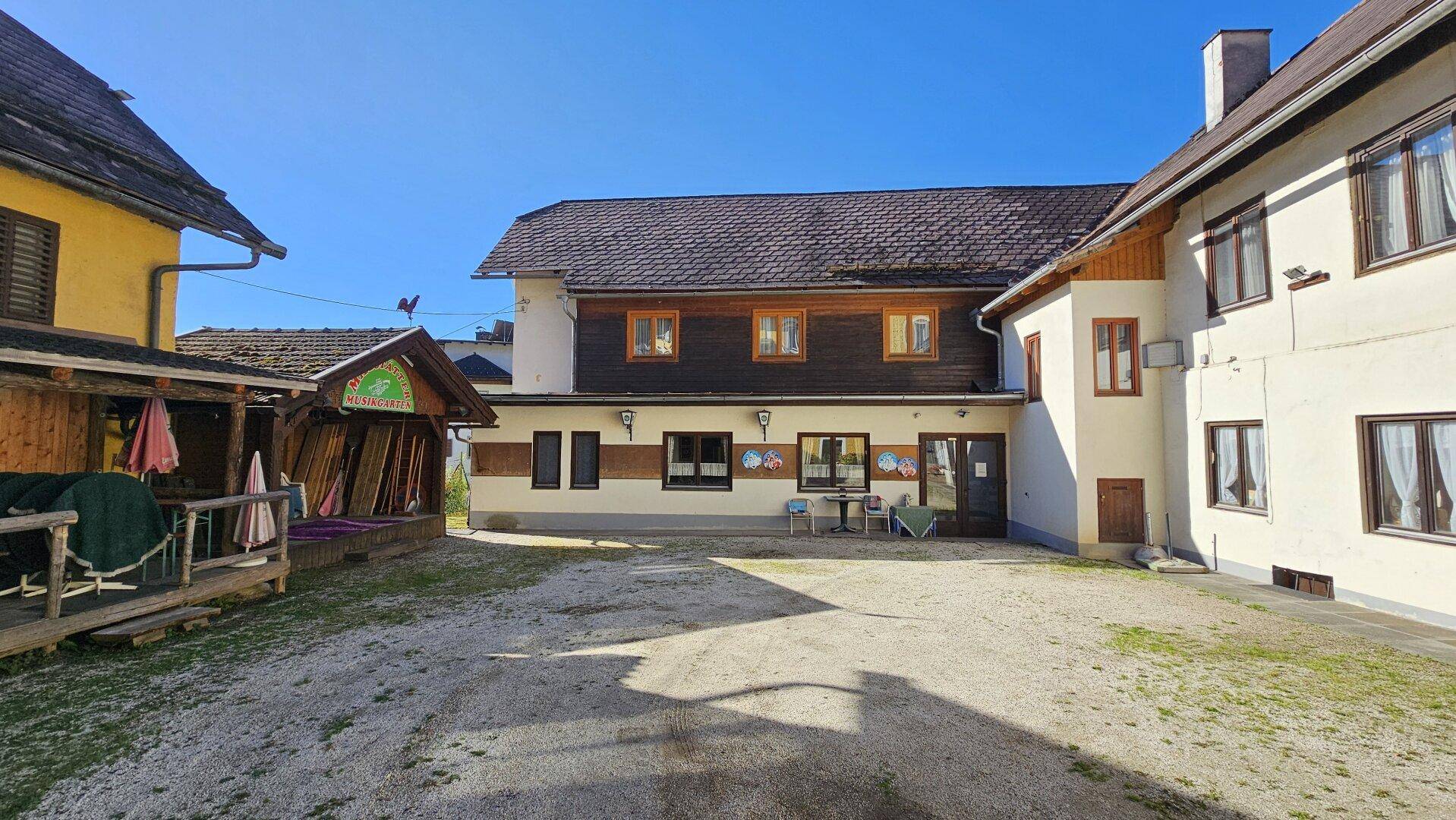 Geräumiger Innenhof mit Kiesboden und einer rustikalen Holzkonstruktion auf der linken Seite.