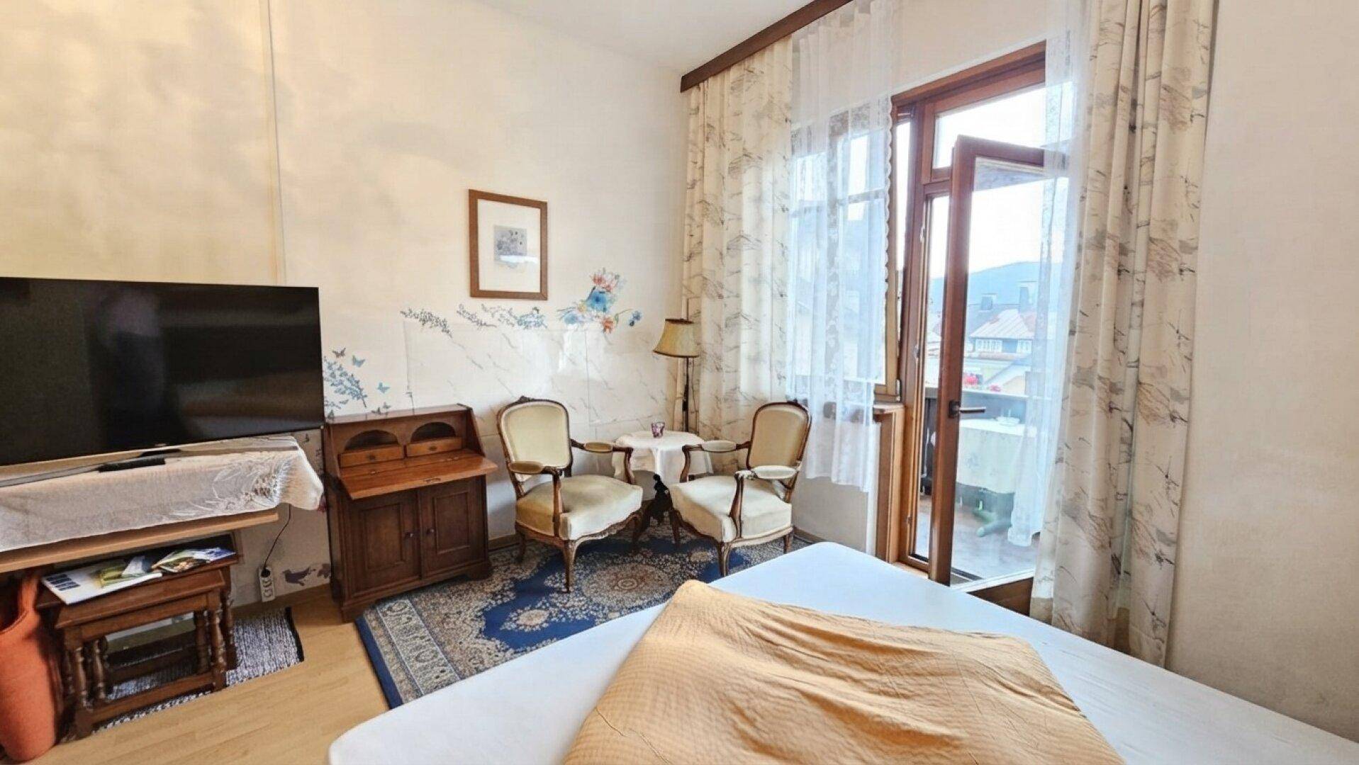 Gemütliches Schlafzimmer mit Doppelbett, antiken Möbeln und Zugang zu einem Balkon mit Aussicht.