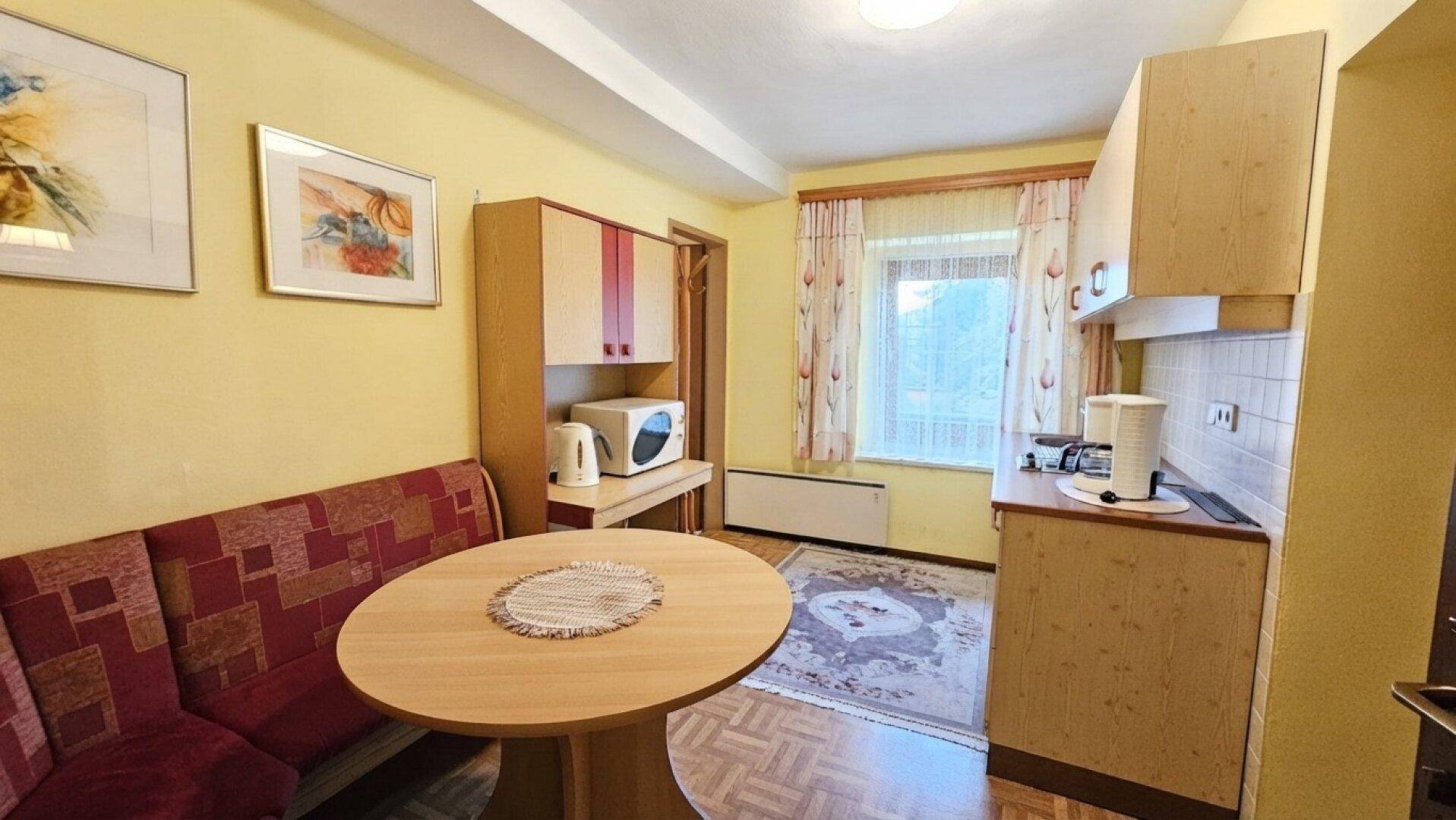 Kleine Küchenzeile mit Essbereich, Mikrowelle und Kühlschrank, ideal für einfache Mahlzeiten.