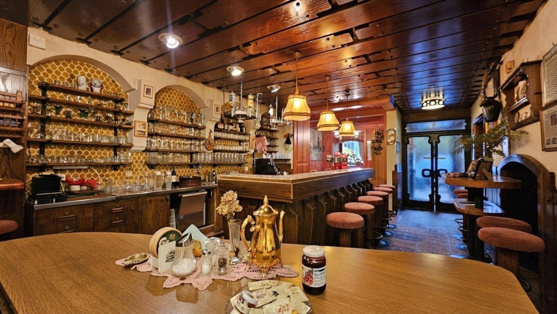 Traditioneller Barbereich mit dunklem Holz, gemütlicher Beleuchtung und vielen Gläsern an der Wand.
