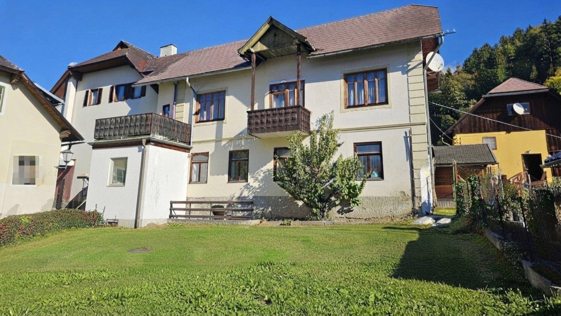 Traditionelles Gebäude mit mehreren Balkonen und einem gepflegten Rasenbereich im Vordergrund.