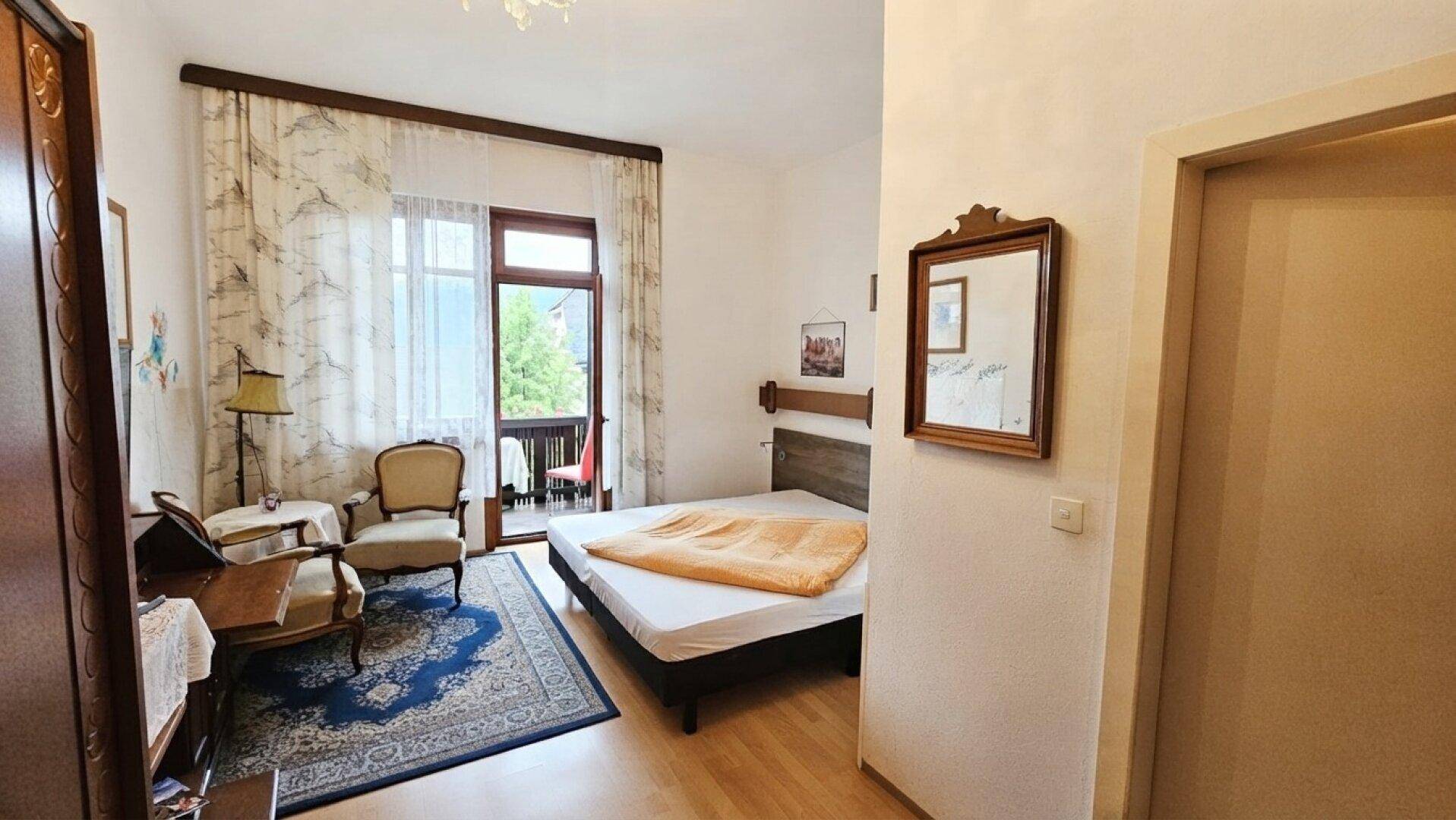 Helles Schlafzimmer mit Doppelbett, klassischer Einrichtung und direktem Zugang zum Balkon.