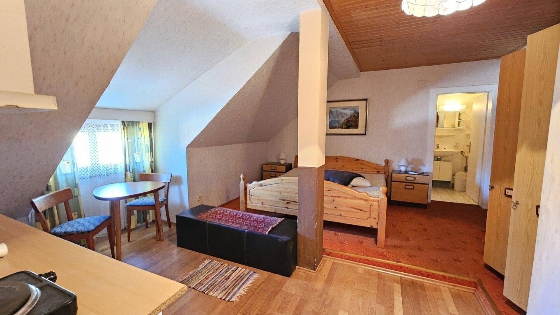 Gemütliches Studio-Apartment mit Schlafbereich, kleiner Essecke und Dachschrägen.