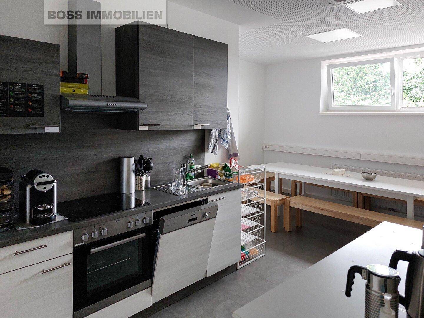 Moderne Küchenzeile mit dunklen Schränken und angrenzendem Essbereich mit Holzbänken.