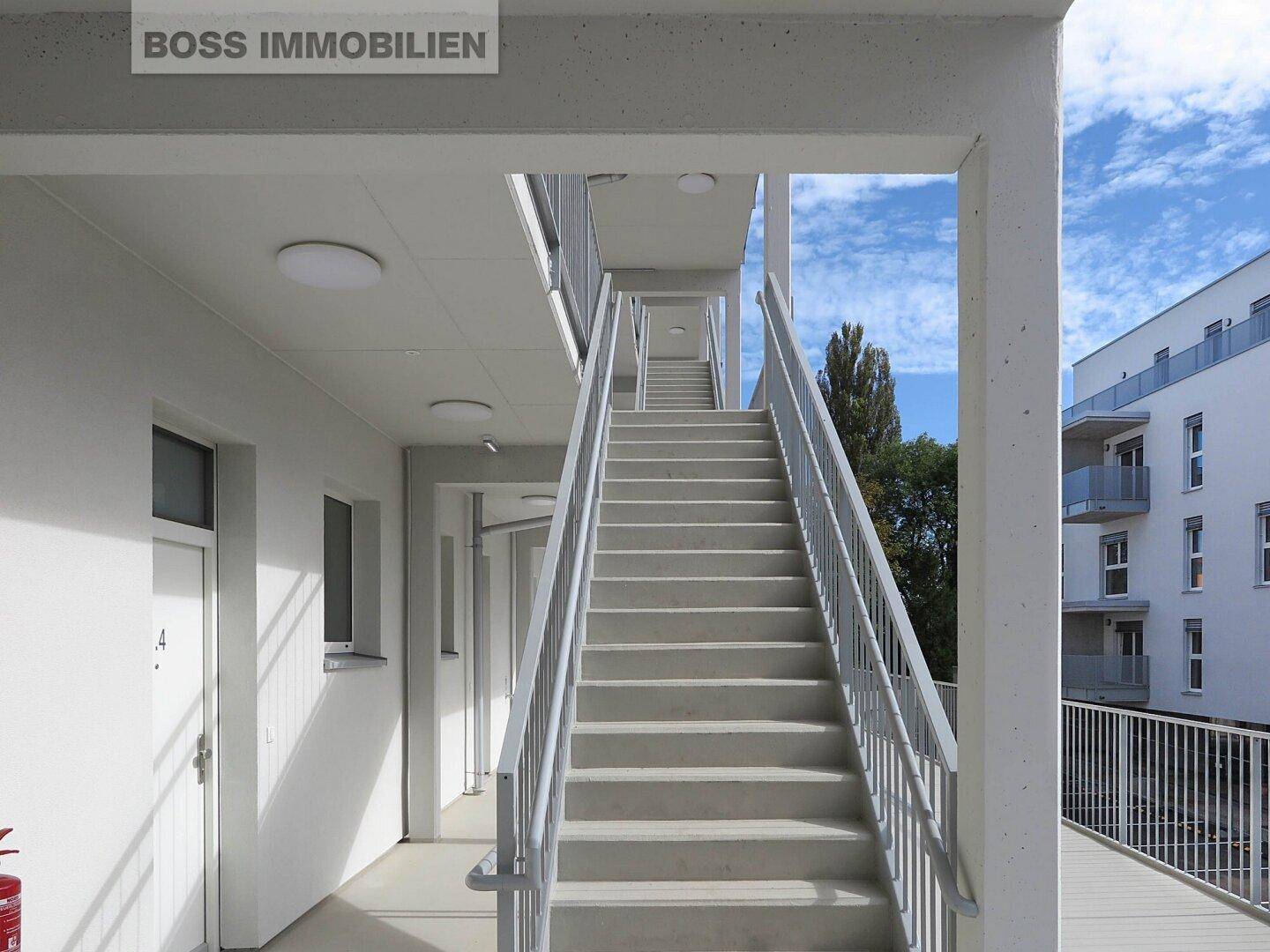 Moderne Außentreppe mit Metallgeländer, die verschiedene Etagen des Gebäudes miteinander verbindet.