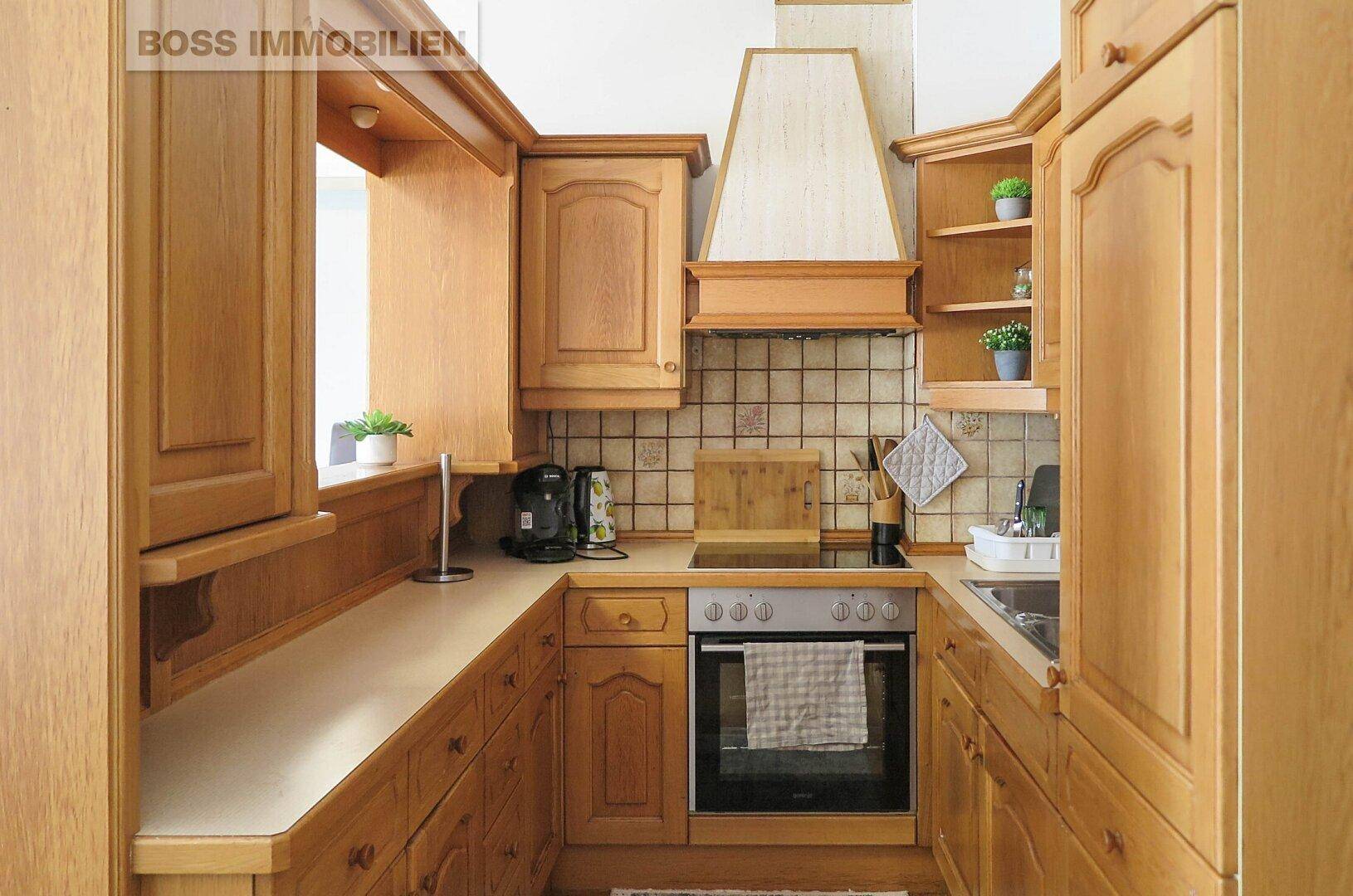 Traditionelle Holzküche mit Einbauschränken, Fliesenrückwand und integriertem Backofen.