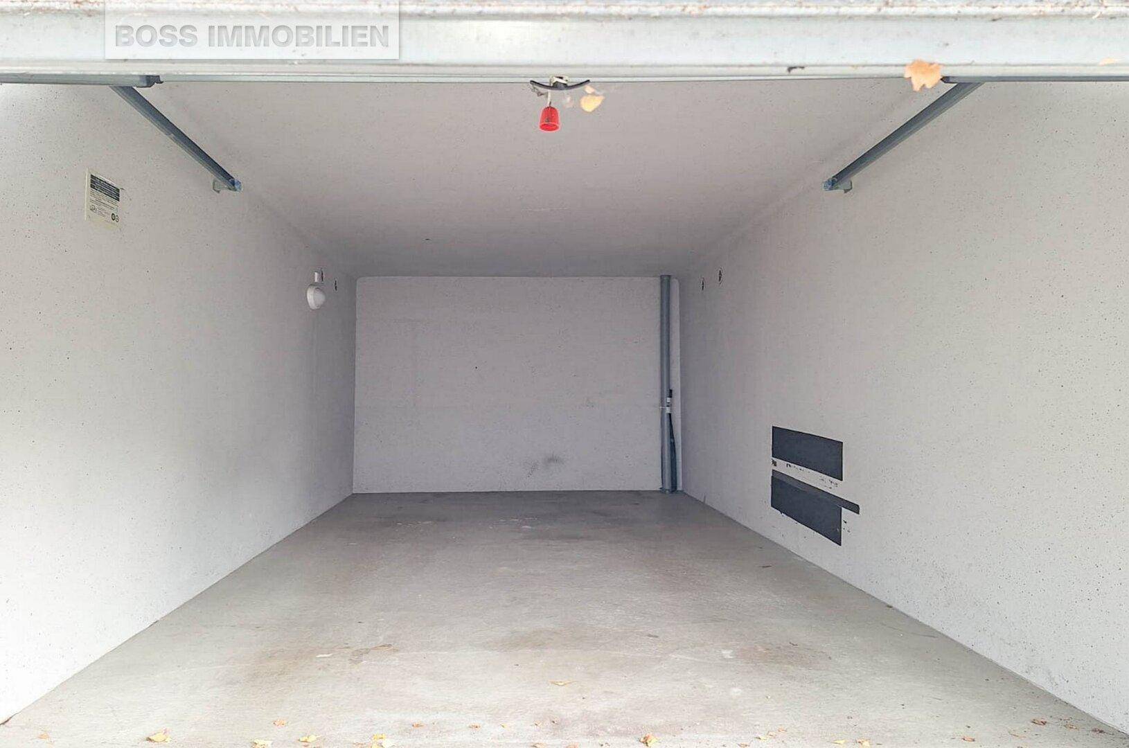 Leere, saubere Garage mit Betonboden und weiß gestrichenen Wänden.
