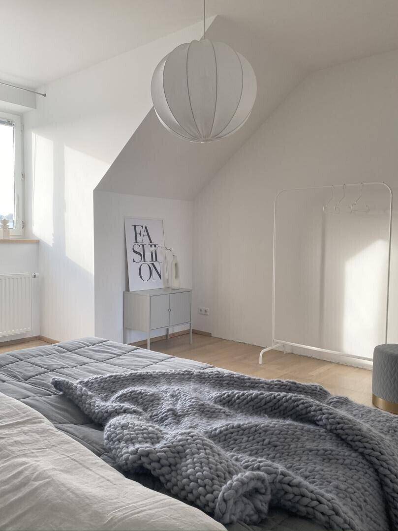 Gemütliches Schlafzimmer mit großem Bett und weichen Textilien in hellem Ambiente.