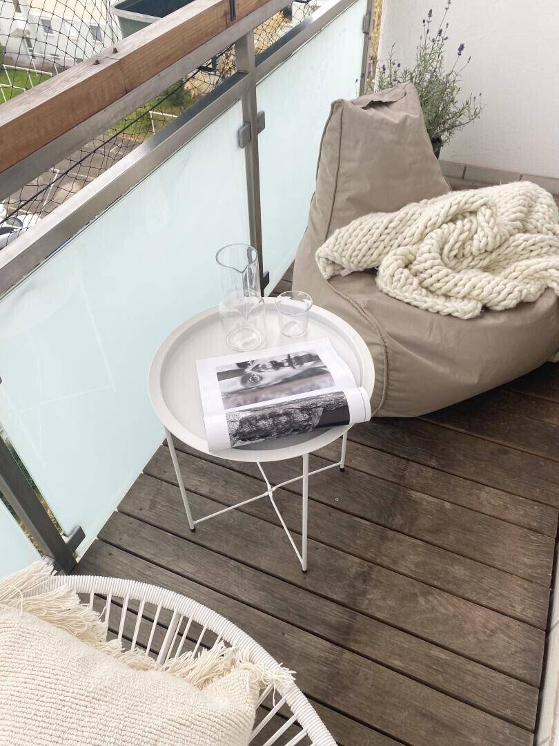 Gemütlicher Balkon mit Holzboden, Sitzsack und Beistelltisch für entspannte Stunden.