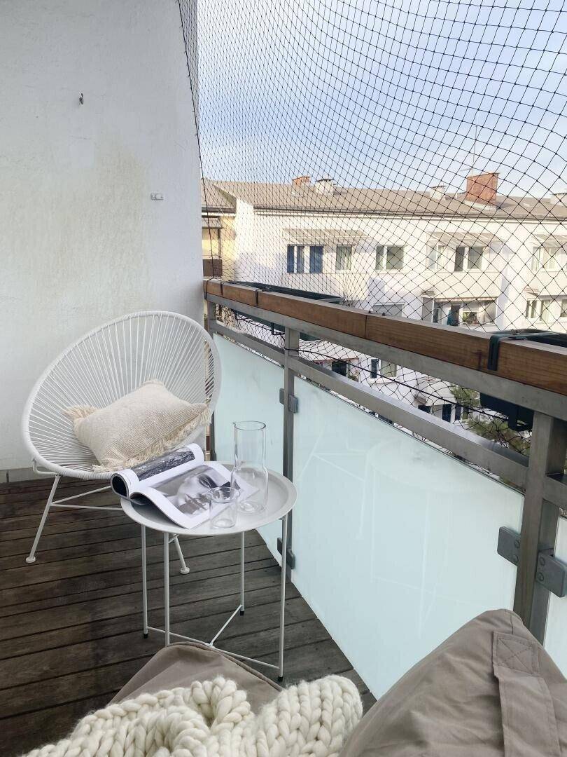 Balkon mit Holzboden und Blick auf die umliegenden Gebäude und den Himmel.