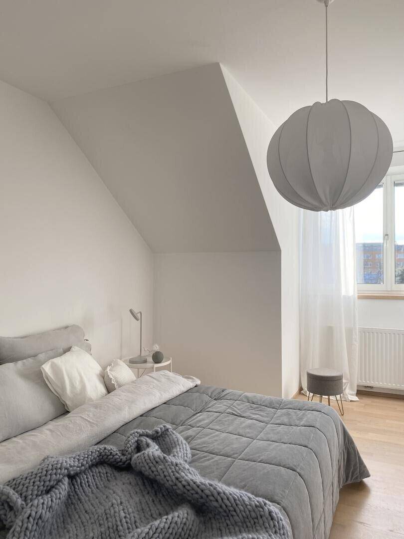 Helles Schlafzimmer mit Dachschräge, großem Bett und Holzboden.