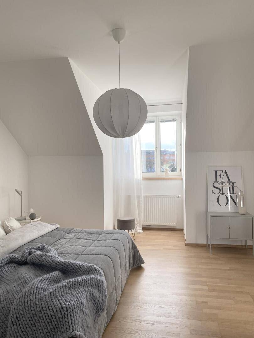 Geräumiges Schlafzimmer mit viel Tageslicht und moderner Einrichtung unter der Dachschräge.