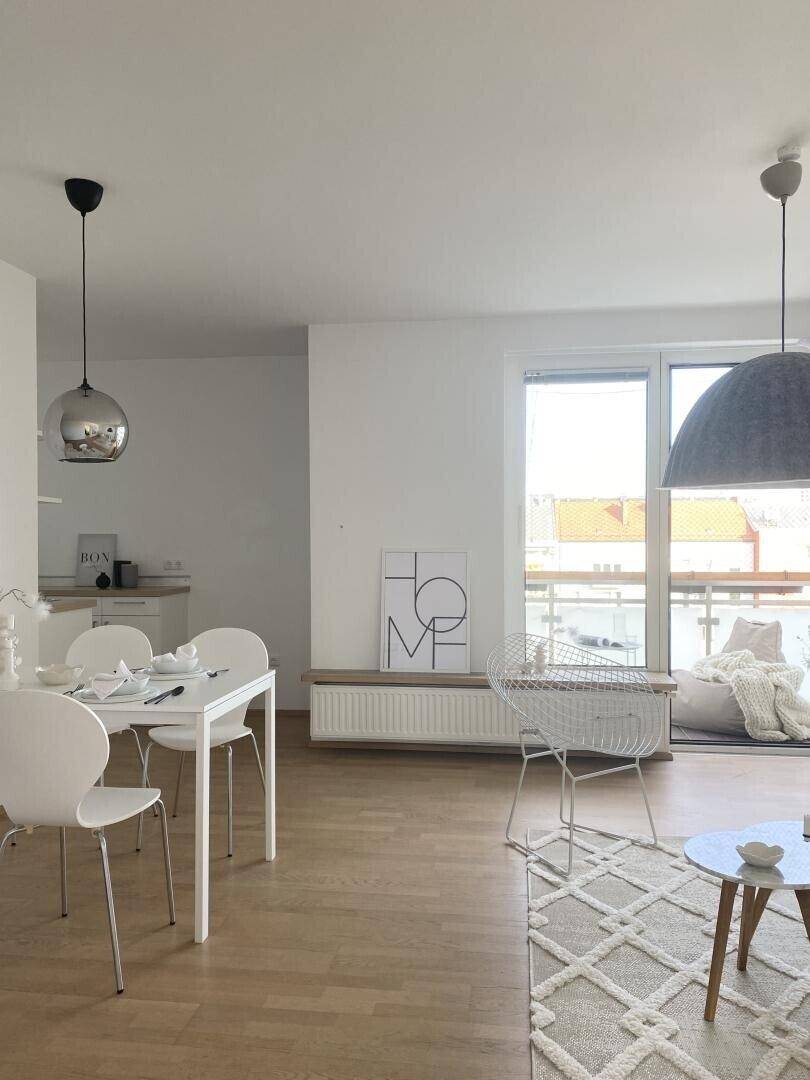 Essbereich mit Zugang zum Balkon und hellem Holzboden in modernem Ambiente.