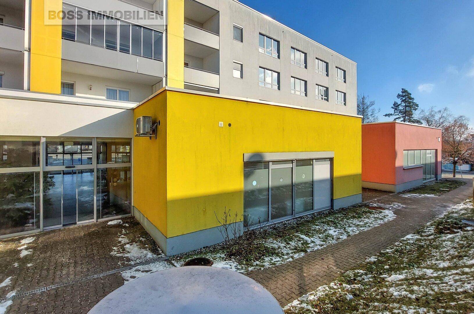Modernes Gebäude mit gelber Fassade und großen Fenstern, umgeben von Schnee.
