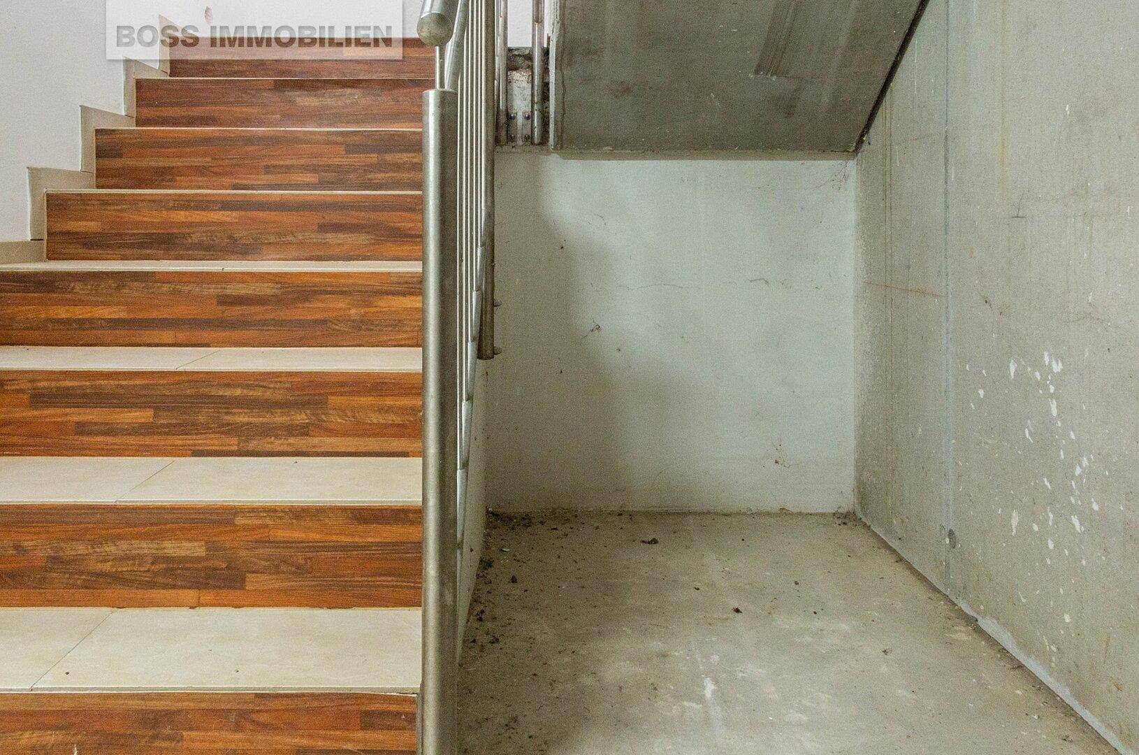 Treppenhaus mit Holzstufen und Metallgeländer, das zu den oberen Etagen führt.