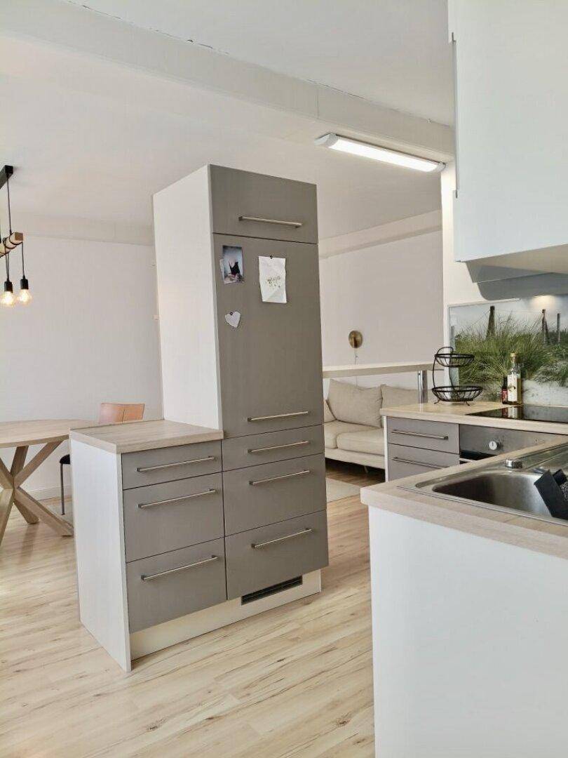 Moderne Küche mit grauen Schränken und integriertem Kühlschrank, offen zum Essbereich.