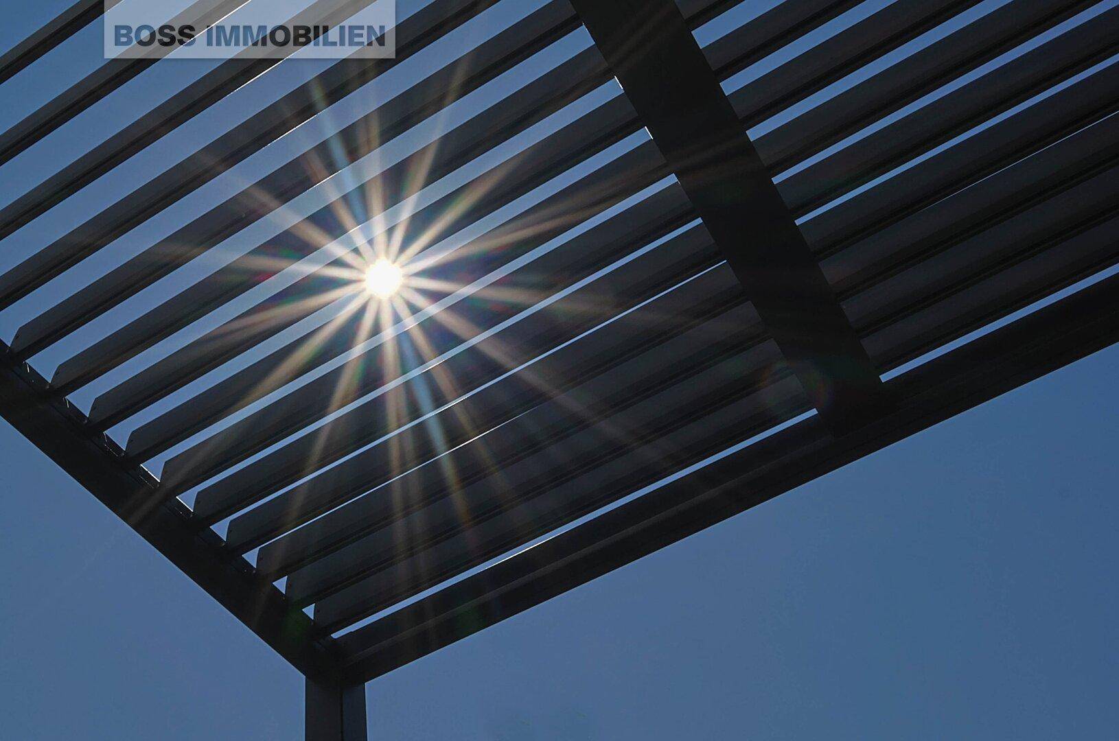 Sonnenlicht fällt durch die Lamellen einer modernen Pergola.