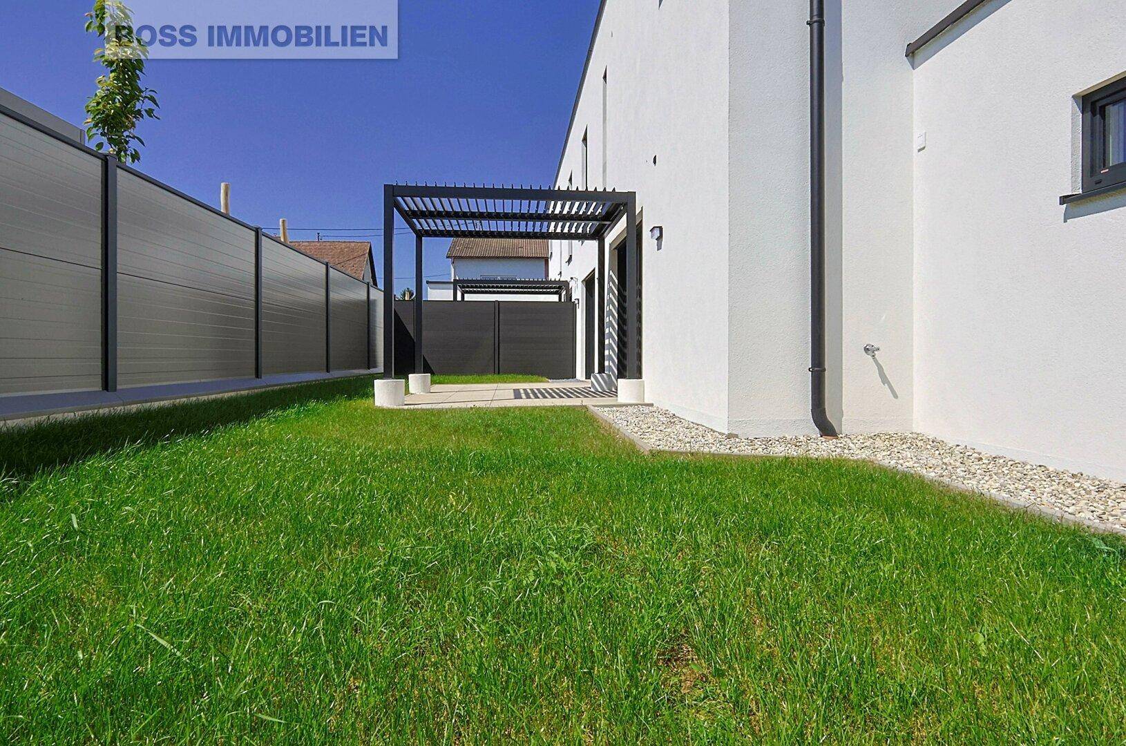 Gepflegte Rasenfläche neben dem Haus mit moderner Zaunanlage.