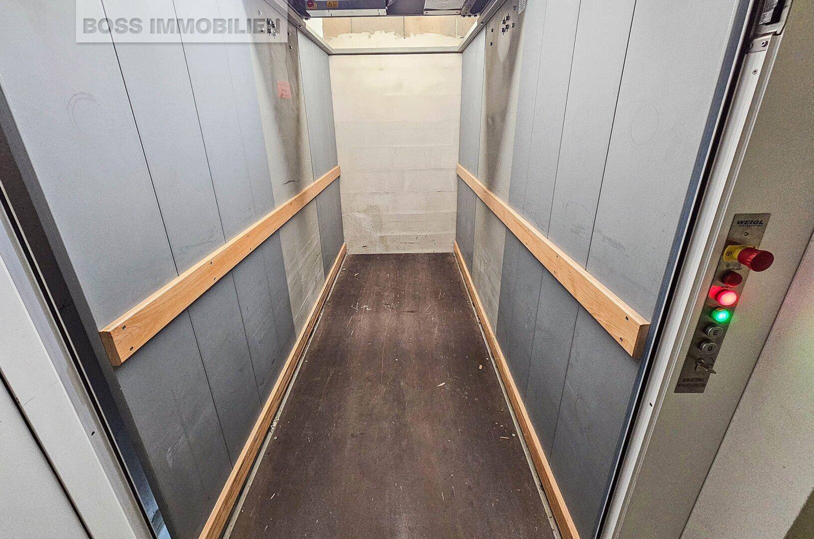 Innenansicht eines Lastenaufzugs mit Holzschutzleisten und Bedienfeld, bereit für den Transport.