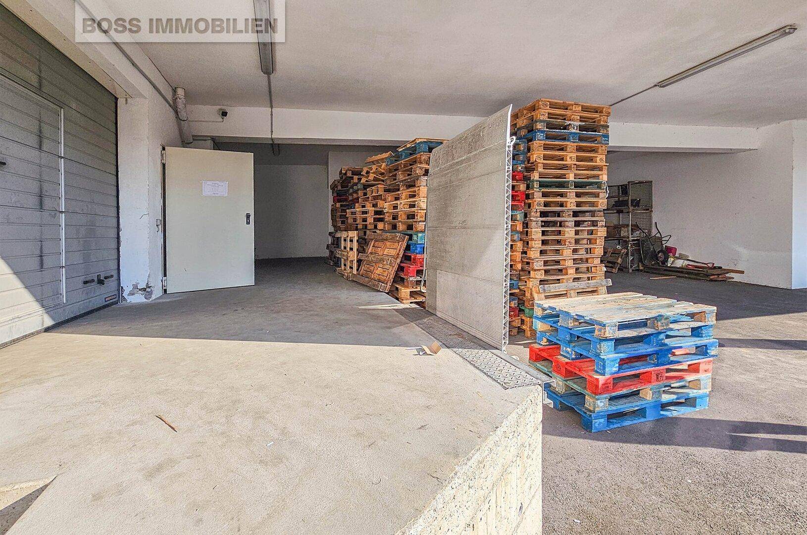 Eingangsbereich eines Lagers mit Rolltor und gestapelten Paletten, ideal für Logistik.