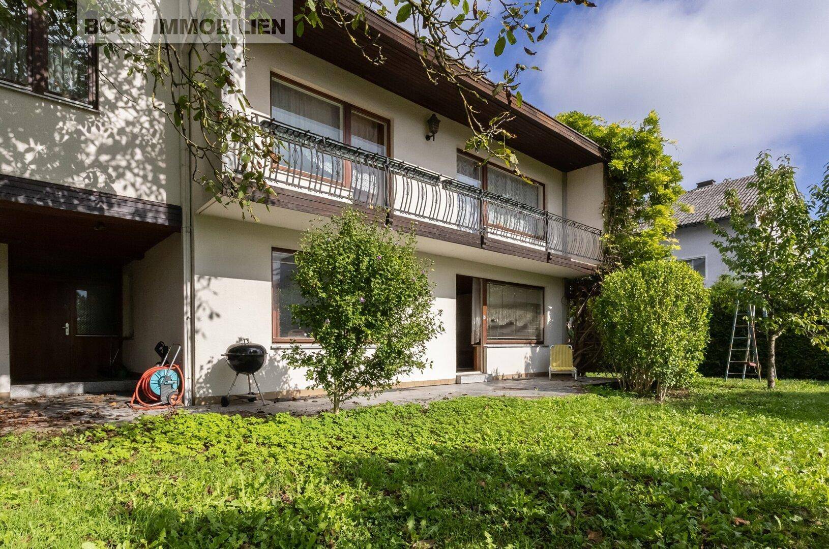 Rückansicht des Hauses mit Rasenfläche, kleiner Terrasse und Grillbereich.
