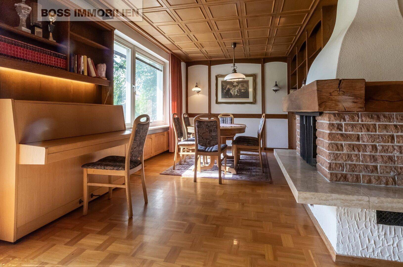 Heller Wohn- und Essbereich mit Parkettboden, Kamin und Holzmöbeln.