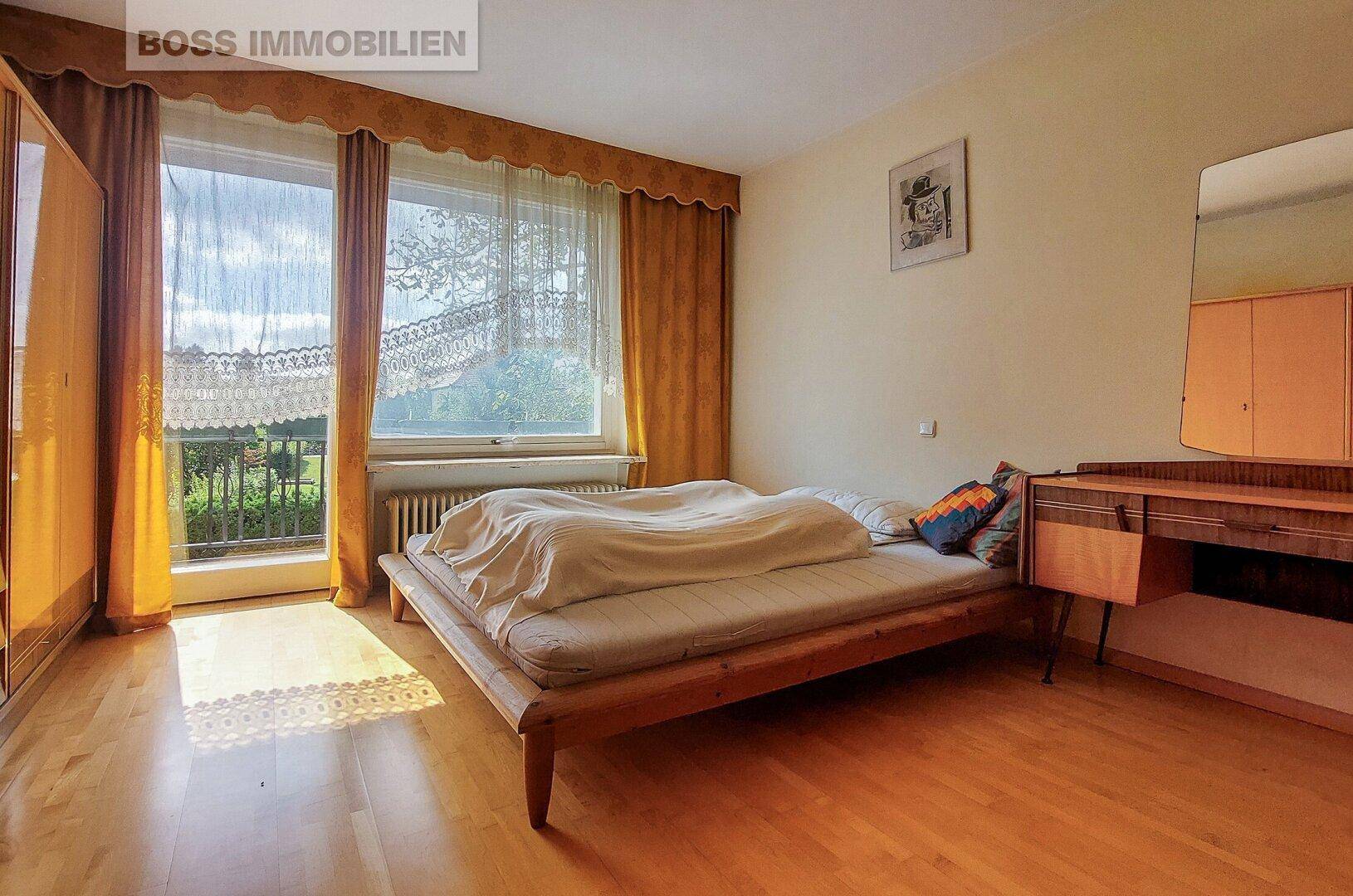 Helles Schlafzimmer mit Holzboden, Doppelbett und Zugang zum Balkon.